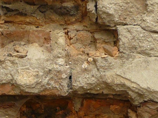 Old brick wall texture covered in thick layer of concrete with very decrepit surface.
