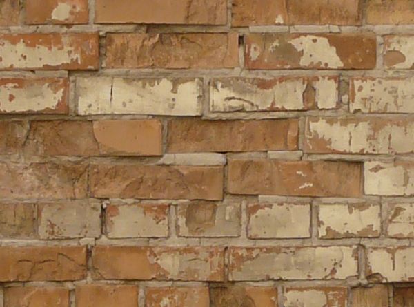 Aged brick wall texture in brown tones painted over in beige color with very worn surface.