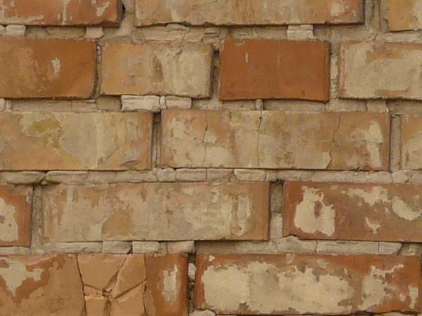 Aged brick wall texture in brown tones painted over in beige color with very worn surface.