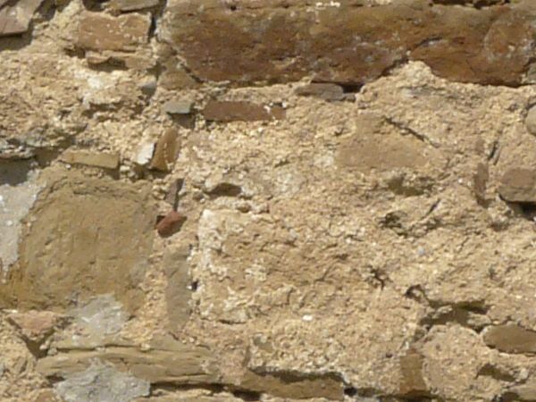 Rough stone wall texture consisting of stones of various shapes and sizes set in beige concrete.