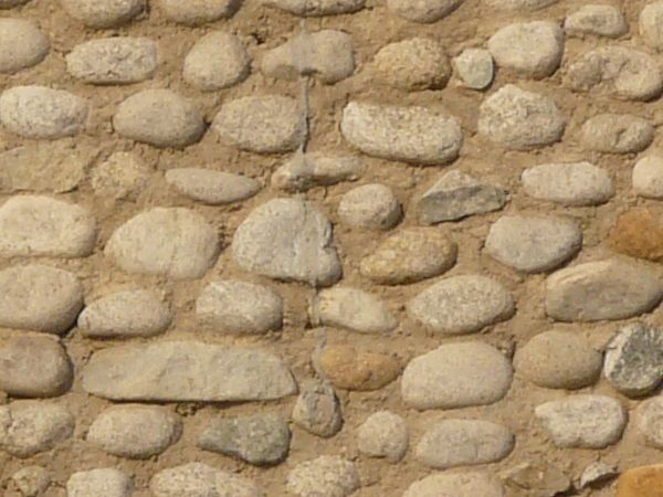 Texture of small, round stones set evenly in brown concrete.