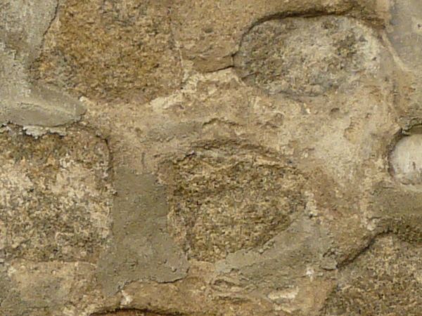 Medieval stone wall texture with large stones sunken in thick, grey concrete.