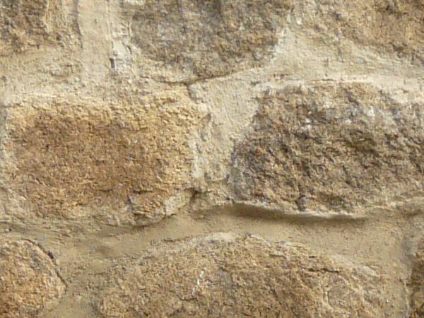 Texture of medieval, stone wall in beige and brown colors set in uneven formation.