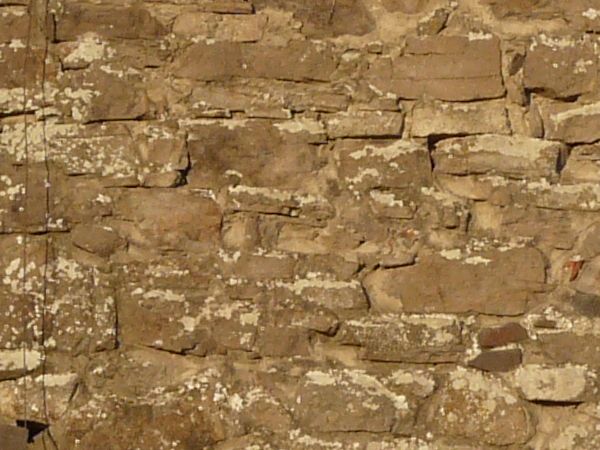 Medieval stone wall texture with holes and worn surface.