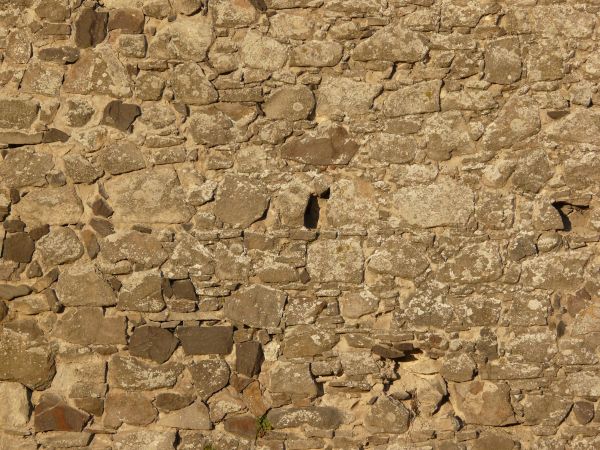 Medieval stone wall texture with holes and worn surface.