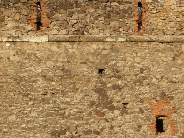 Medieval stone wall texture with holes and worn surface.