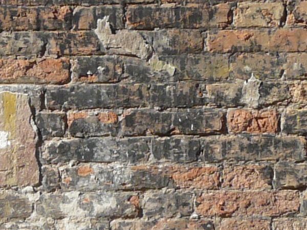 Red brick texture with large areas of dark and light discoloration, and several areas patched by cement.