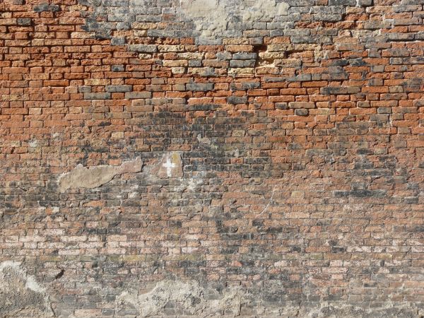 Red brick texture with large areas of dark and light discoloration, and several areas patched by cement.