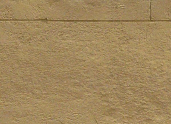 Large bricks laid in wall and painted over in light beige tone.