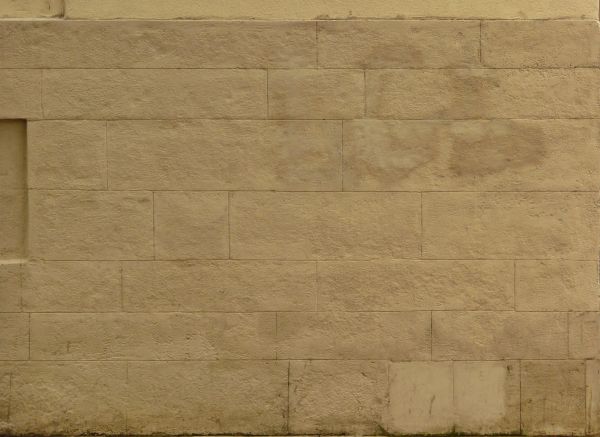 Large bricks laid in wall and painted over in light beige tone.