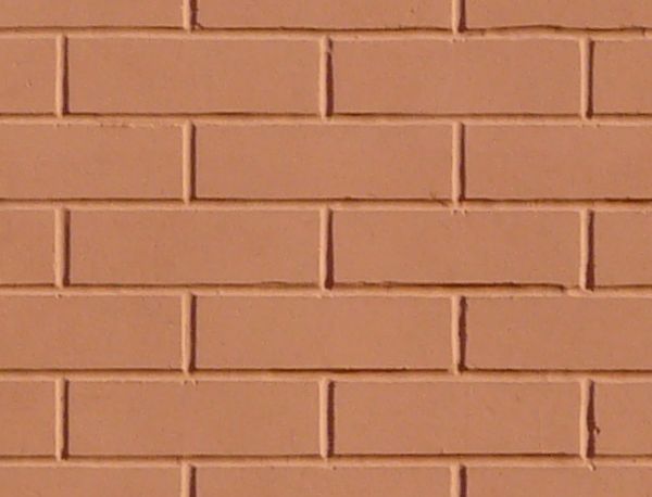 New brick wall laid evenly and painted over in light red tone.