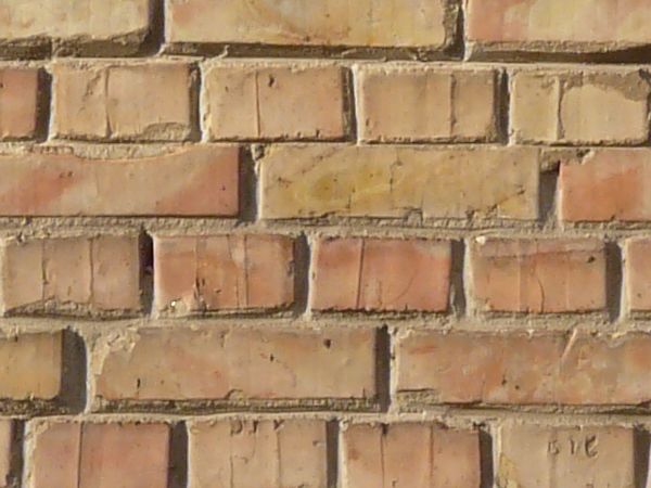 Brick wall laid evenly in beige color with light brown brick set randomly throughout.