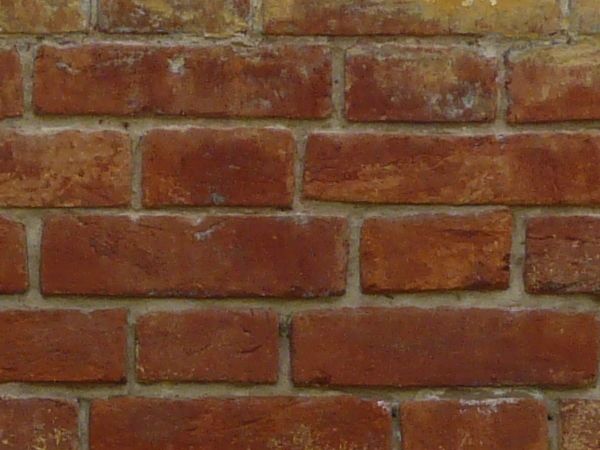 Red brick wall painted in several layers of various colors.