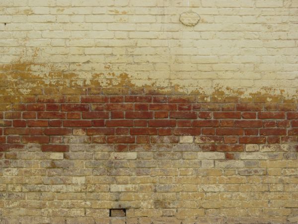 Red brick wall painted in several layers of various colors.