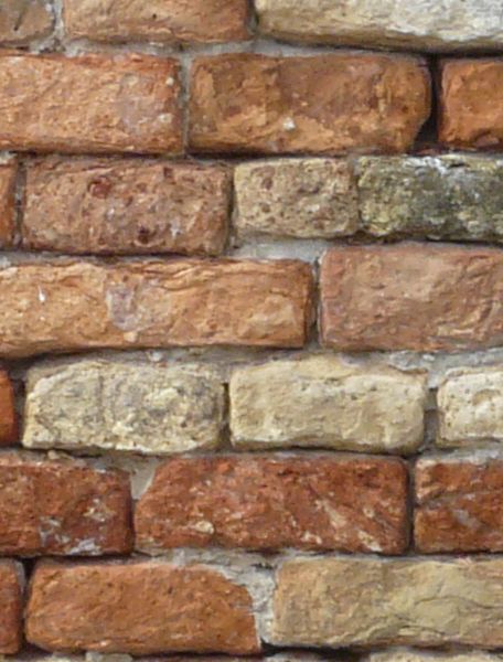 Red brick wall with white spots and round-edged bricks.