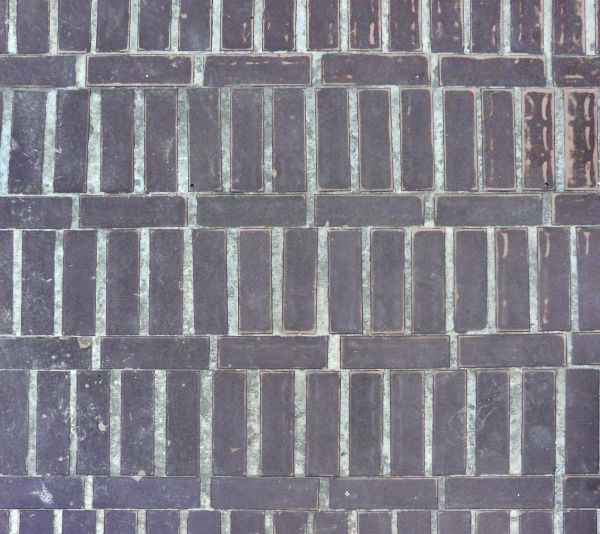 Cobblestone texture of dark, rectangular blocks set in grey cement.