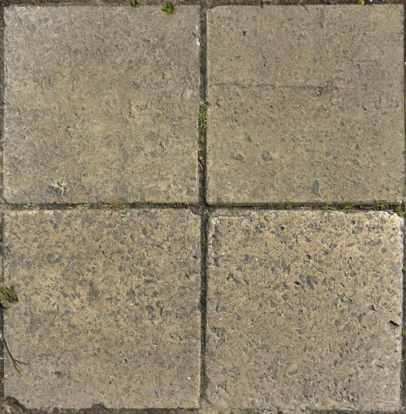 Old square tiles in beige tone with very rough surface and some vegetation in cracks.