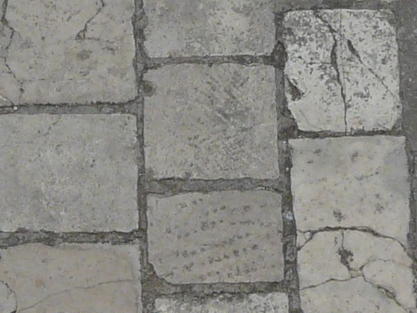 Seamless pavement texture consisting of grey stones of various shapes with worn surface.