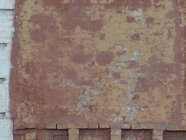 Texture of two-storey building with brick wall painted in red tone. Surface of wall is very worn and dirty.