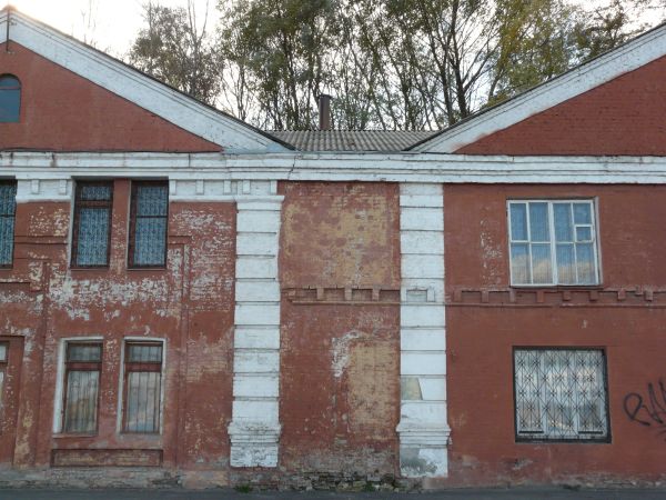 Texture of two-storey building with brick wall painted in red tone. Surface of wall is very worn and dirty.