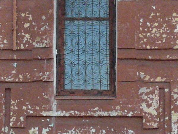 Texture of two-storey building with brick wall painted in red tone. Surface of wall is very worn and dirty.