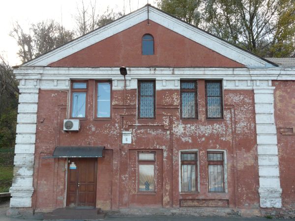 Texture of two-storey building with brick wall painted in red tone. Surface of wall is very worn and dirty.