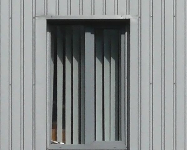 Simple building with walls of lined sheet metal in grey color.
