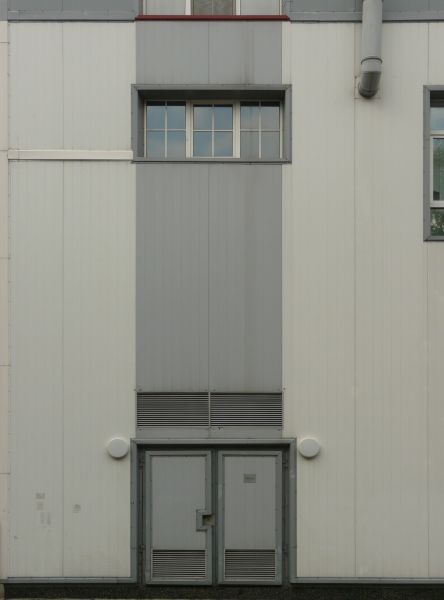 Large building with simple, metal siding painted in alternating, grey tones.