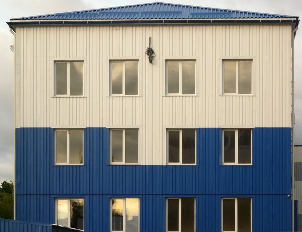 Large building with lined, metal walls painted in blue and beige tones.