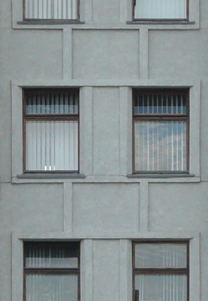 Large, multi-storey building of dull, grey concrete with windows.