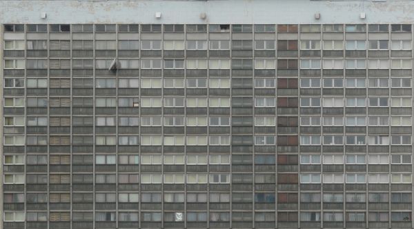 Old, multi-storey building with a very dull, concrete fa��ade with windows.