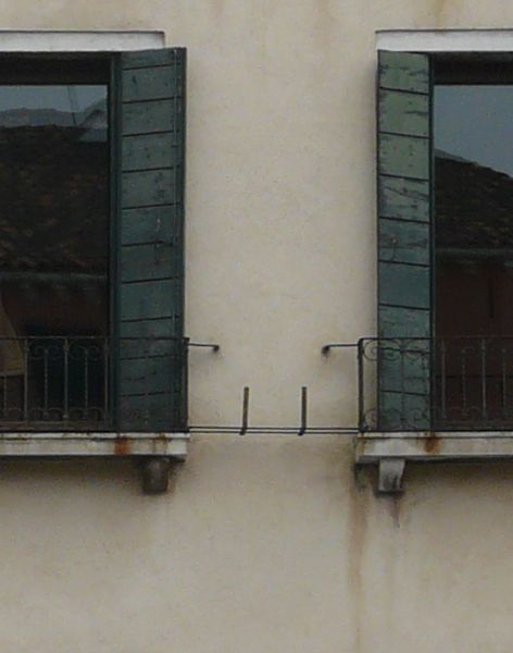 Simple, aged multi-storey building with very worn, beige surface and square windows.