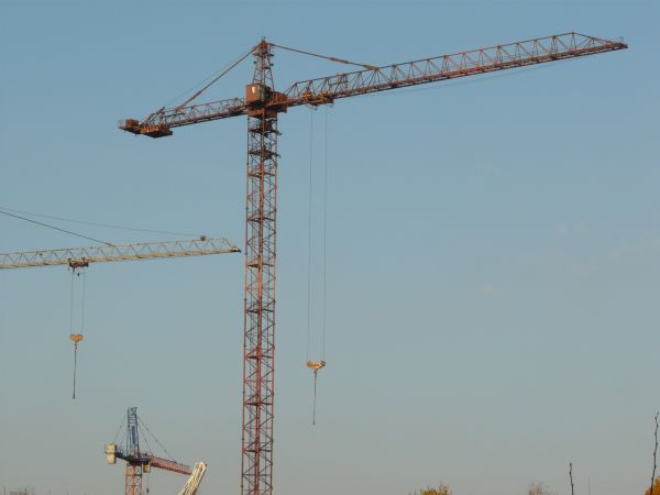 Red crane texture, made up of a lattice of painted steel beams. Pieces of two other yellow cranes are also visible.
