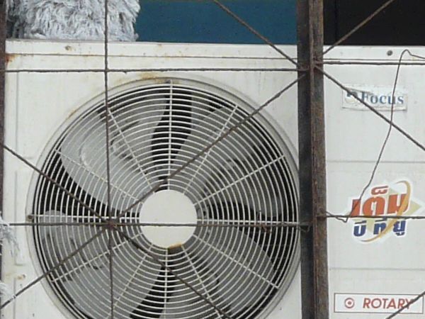 Air conditioners texture, stacked among various other materials, and set in an aged white brick wall.