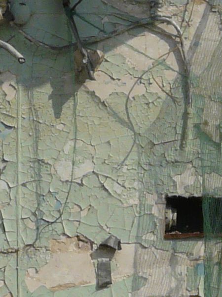 Aged wall of beige brick and thin layer of worn concrete with irregular, decrepit consistency.