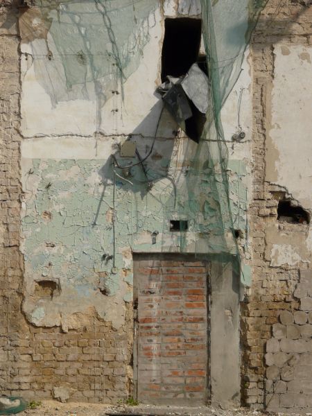 Aged wall of beige brick and thin layer of worn concrete with irregular, decrepit consistency.