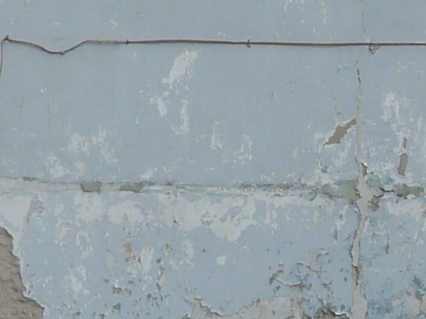 Old, large wall texture of brick and worn concrete with very damaged, irregular surface and hanging nets.