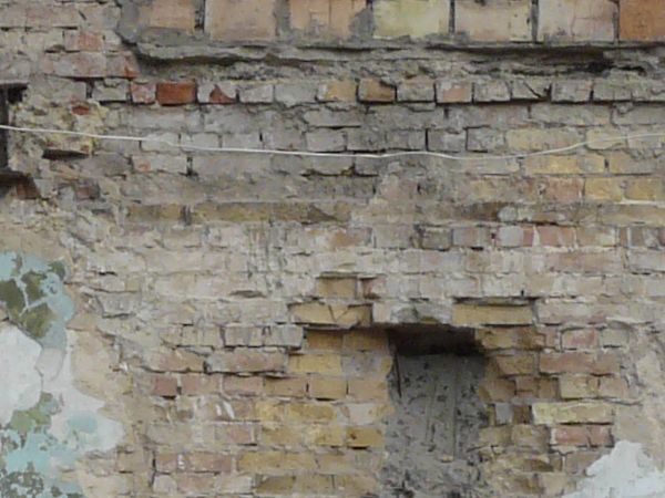 Old, large wall texture of brick and worn concrete with very damaged, irregular surface and hanging nets.