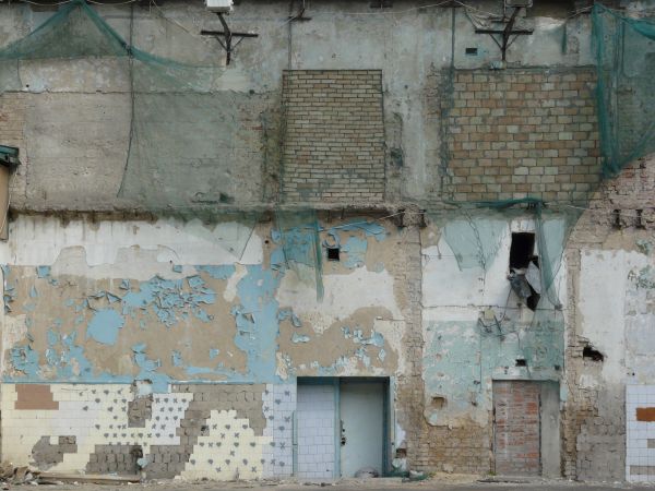 Old, large wall texture of brick and worn concrete with very damaged, irregular surface and hanging nets.