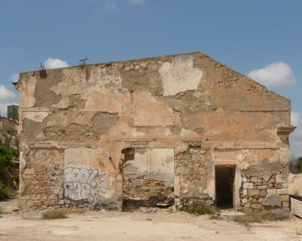 Ruins of large walls made of brick covered in thin layer of concrete. Surface of walls is very damaged.