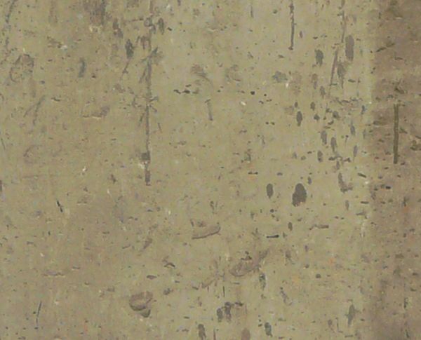 Worn concrete texture in light tan tone with dark streaks and scratches on surface.