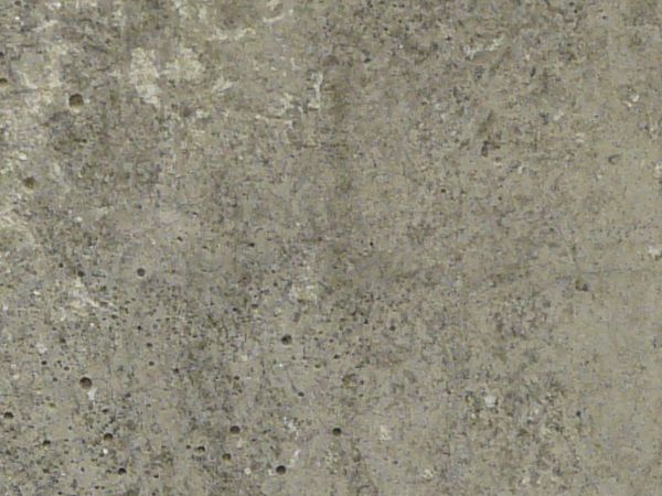 Old concrete base in grey tone with small holes in surface and dark streaks on top.