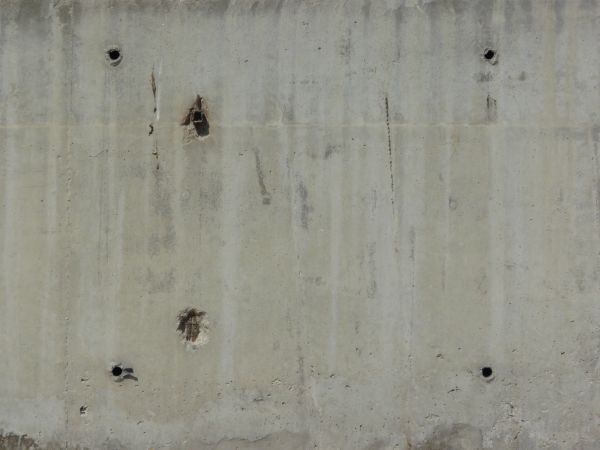 Concrete slab texture with light streaks and large holes in surface.