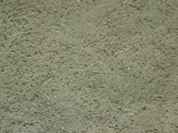 Concrete texture in unnatural, pale green color with very rough surface and small holes.