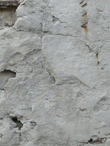 Very damaged concrete surface with exposed metal mesh and rust armature.