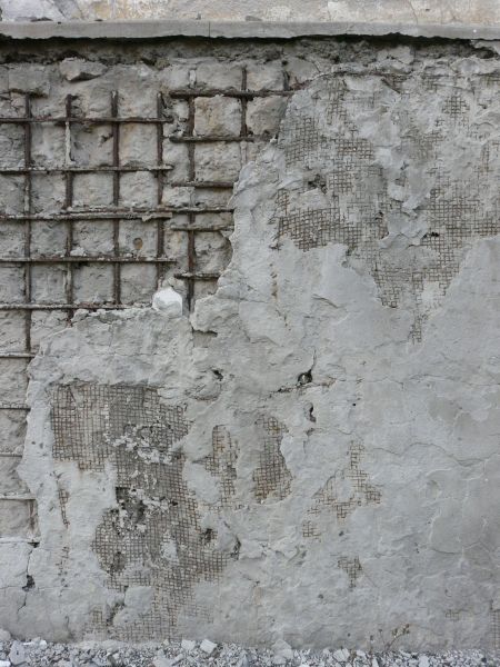 Very damaged concrete surface with exposed metal mesh and rust armature.