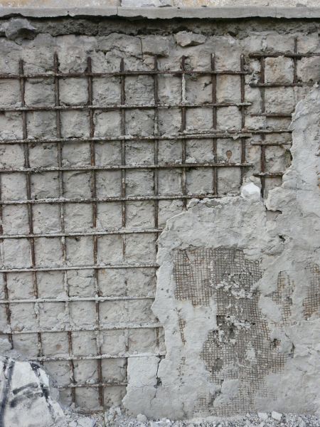 Very damaged concrete surface with exposed metal mesh and rust armature.