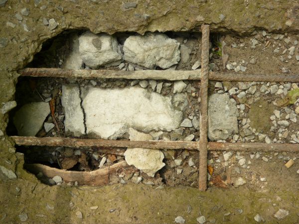 Rough concrete texture in dark green color with large hole and rusty armature in center.