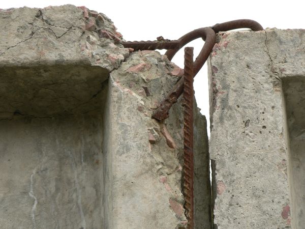 Concrete structure with damaged, crumbling surface and iron infrastructure.