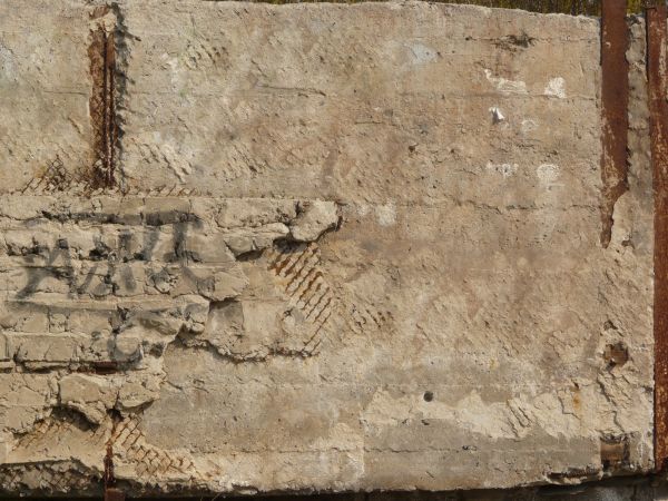 Very rough, damaged concrete in light beige color settled over rusty, metal mesh.